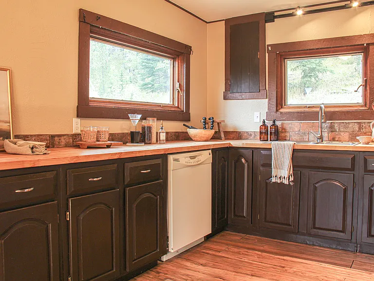 Large gourmet kitchen with a huge expanse of new butcher block countertops extending around the room and windows looking out into nature