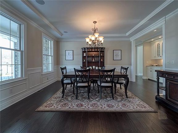An elegant dining room features gleaming hardwood flooring, wainscoting, surround sound, a tray ceiling, intricate trim detailin