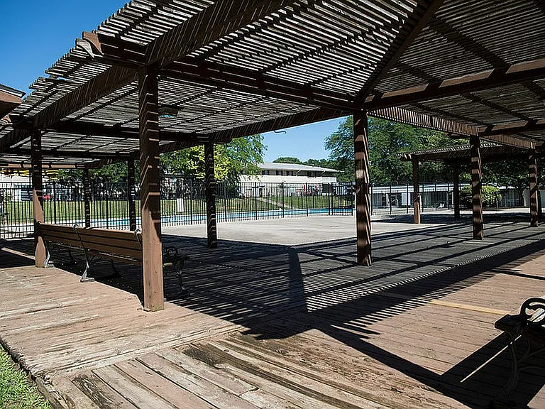 Inviting outdoor patio area with rustic wooden pergolas and bench seating, perfect for relaxation and leisure.