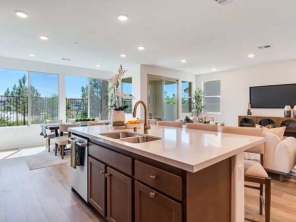 A modern and spacious kitchen with a large island, wooden cabinets, and large windows overlooking a