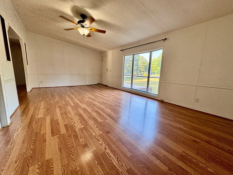 Bright, oversized living room featuring hardwood floors, a large bay window overlooking the front yard, and direct access to the front porch. Plenty of space for family gatherings and everyday living.