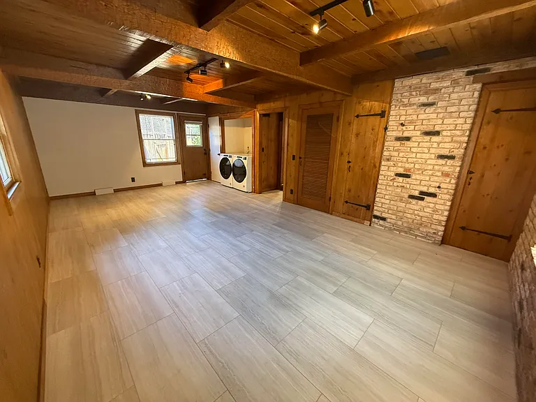Spacious family room featuring wooden beam ceiling, a bay window, storage closets and a laundry closet with patio access to the backyard.