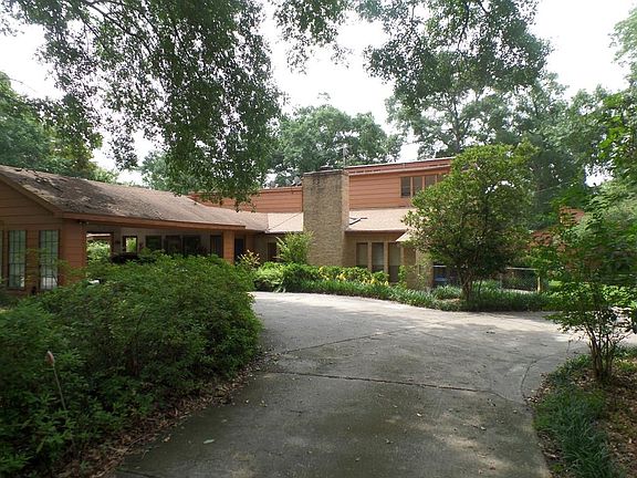 Large great room with a sunk-in conversation pit around a wood burning fireplace, high ceiling and lots of windows.
