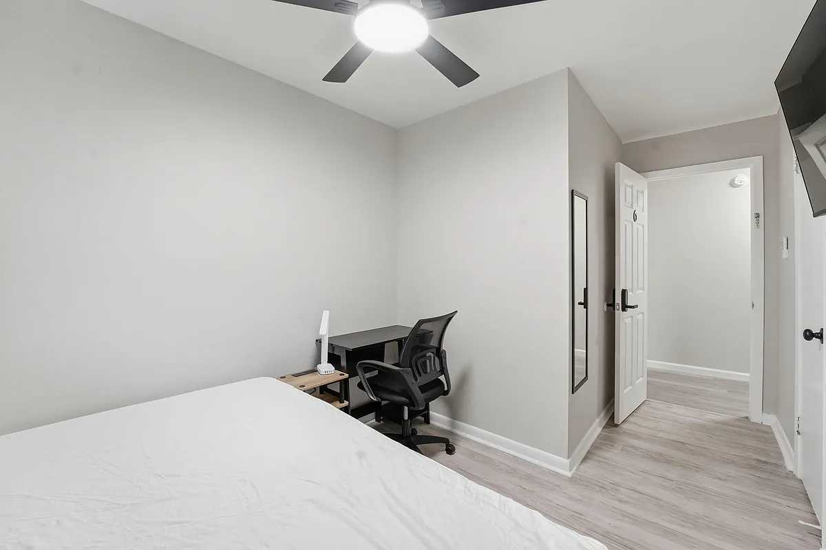 Private bedroom with ceiling fan, wood-look flooring, and space for a bed plus a work desk; convenient access to the hall. - Mulberry Ln
