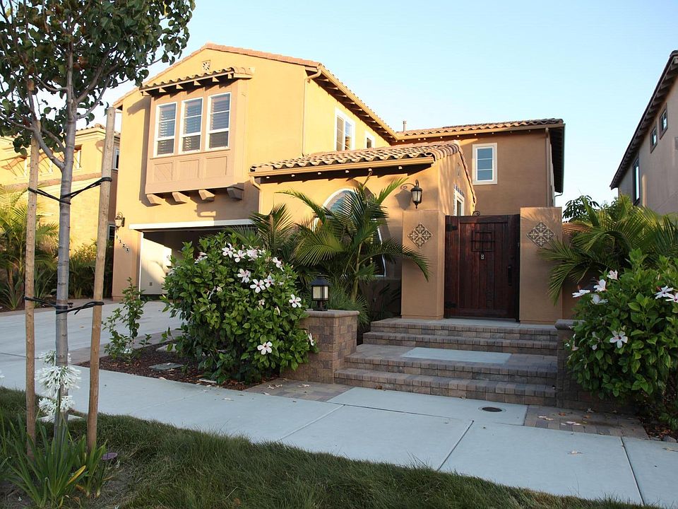 Lush, tropical landscaping with charming "heavy duty" wooden door and decorated tile accents.