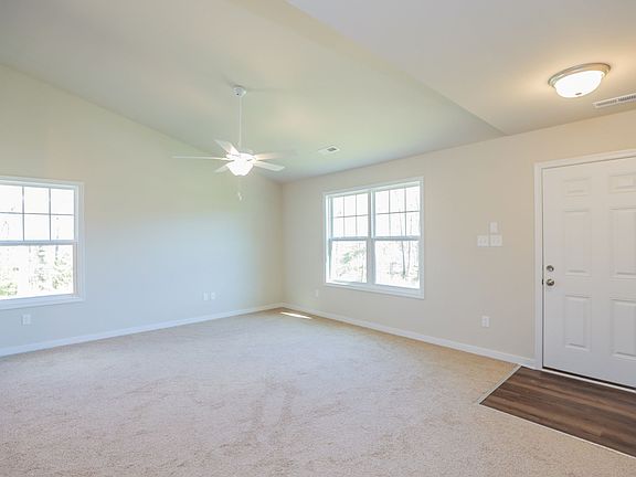 Bright, empty room with beige carpet, ceiling fan, and large windows--perfect for new homes in Richm