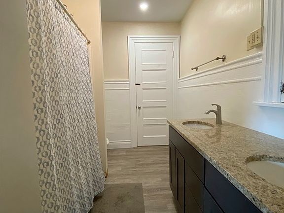 A double vanity sink, tub/shower, and open shelving to decorate or us for storage.