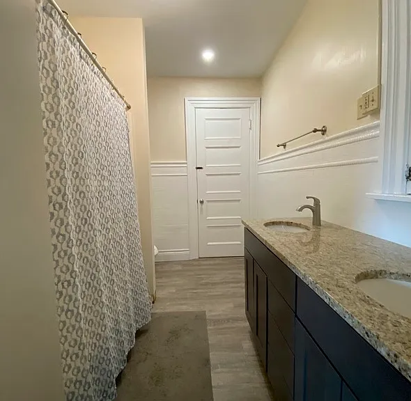 A double vanity sink, tub/shower, and open shelving to decorate or us for storage.
