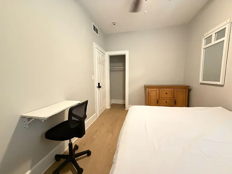 Private bedroom with a bed, built-in closet, and convenient wall-mounted desk for work or study.