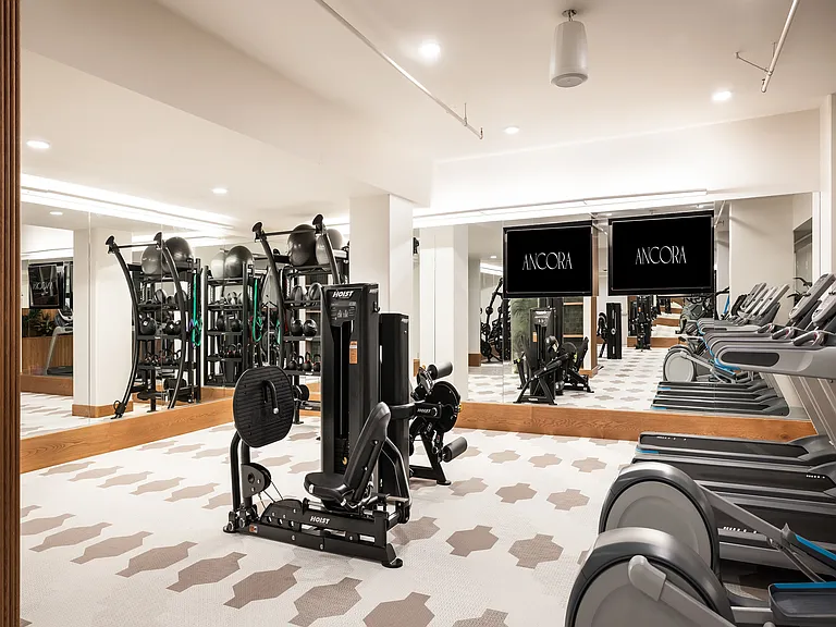 Modern fitness center with state-of-the-art exercise equipment, including treadmills and strength machines, surrounded by mirrors for an open, spacious feel.