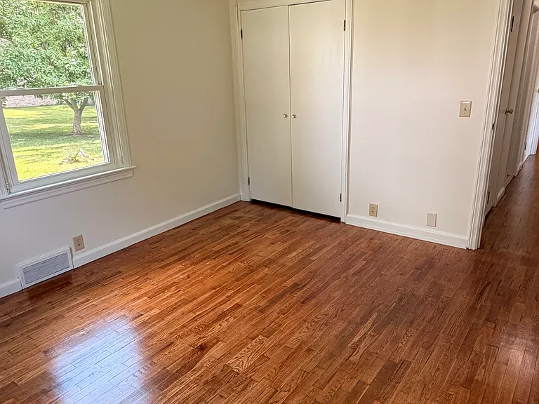 1st bedroom with hardwood floors and another closet