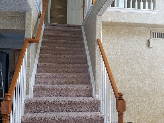 Stairs between living/dining rooms leading to the second floor. To the right of the staircase is a small loft area.
