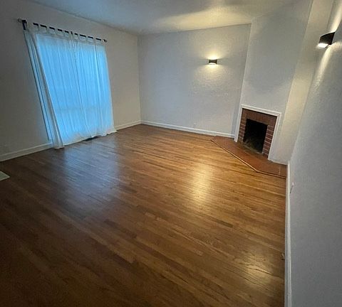 Living Room w/ working Fireplace, newly refinished original wood floors and new double pane windows!