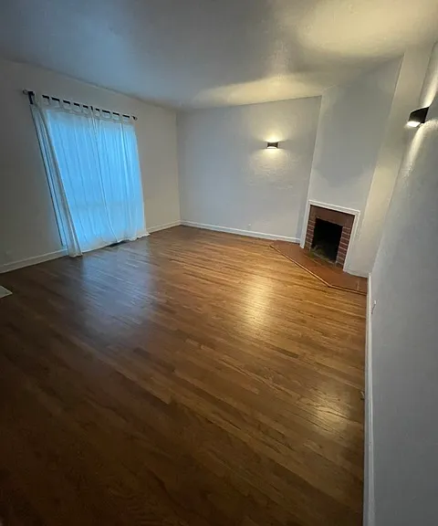 Living Room w/ working Fireplace, newly refinished original wood floors and new double pane windows!