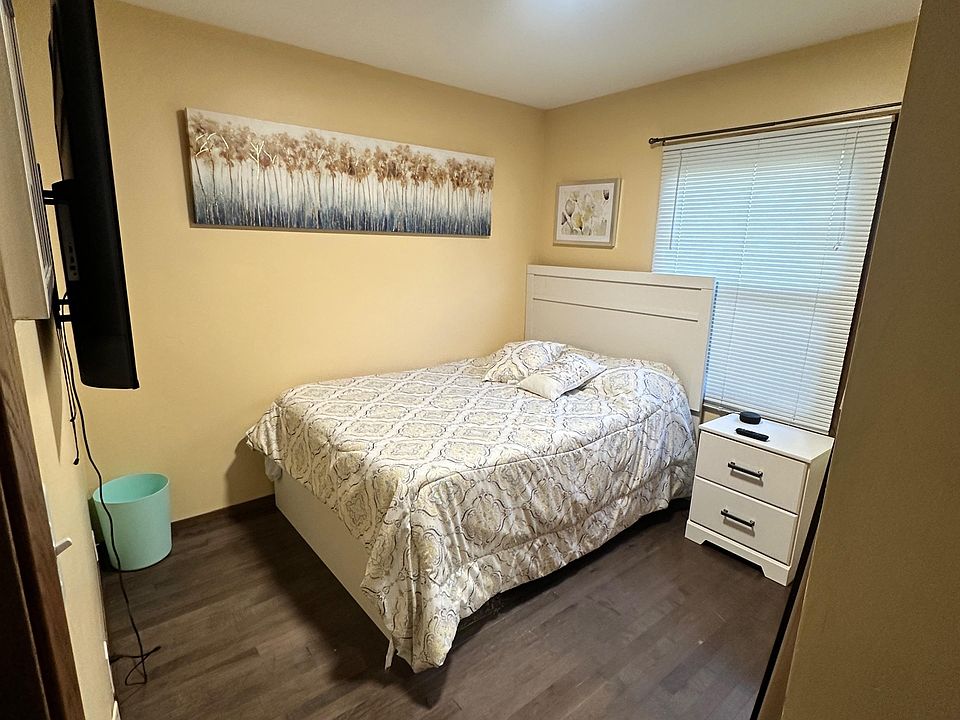 Furnished bedroom with a full bed, nightstand storage, and a window with blinds for light and privacy.