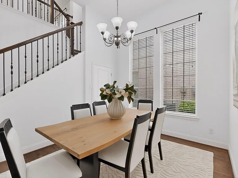 A charming dining area showcasing tall windows and a chandelier, perfect for dining and socializing.