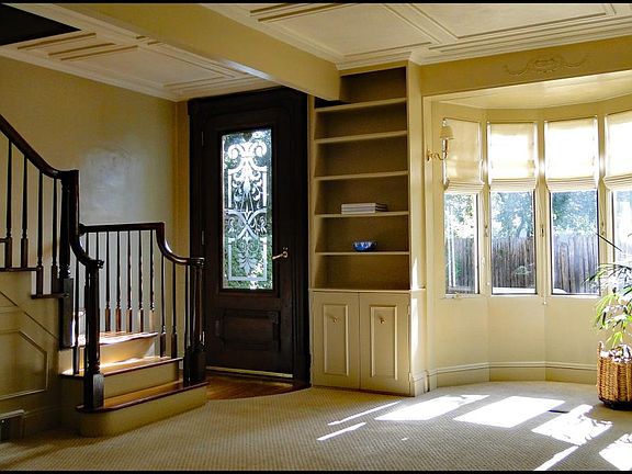 Wool Berber carpet; bookcases bank the five-window bay on a sunny day.