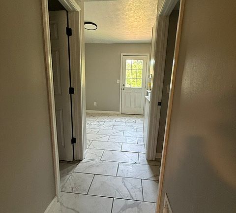 From living room into hallway NEW tile throughout. Left door is half bathroom, right door is laundry room with w/d hook ups