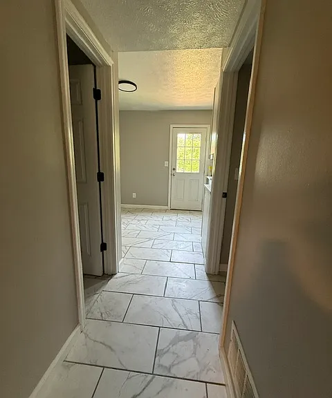 From living room into hallway NEW tile throughout. Left door is half bathroom, right door is laundry room with w/d hook ups
