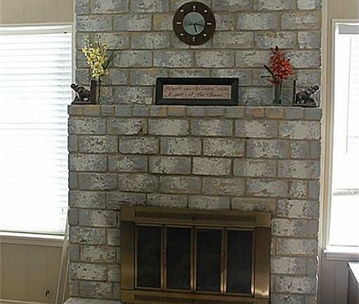 Floor to ceiling brick fireplace, surrounding by windows overlooking backyard area.