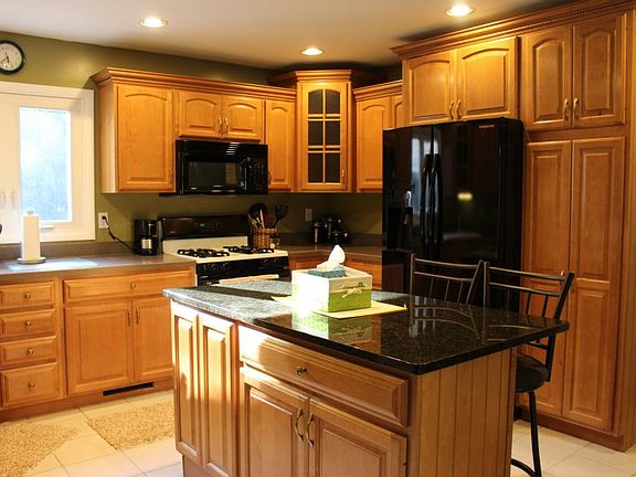 Completely renovated kitchen features new cabinetry, crown molding, granite island, recessed lighting, & tile flooring!