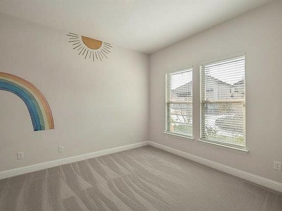 Room featuring light gray wall paint, two windows with horizontal blinds, neutral-toned carpet, and white baseboards