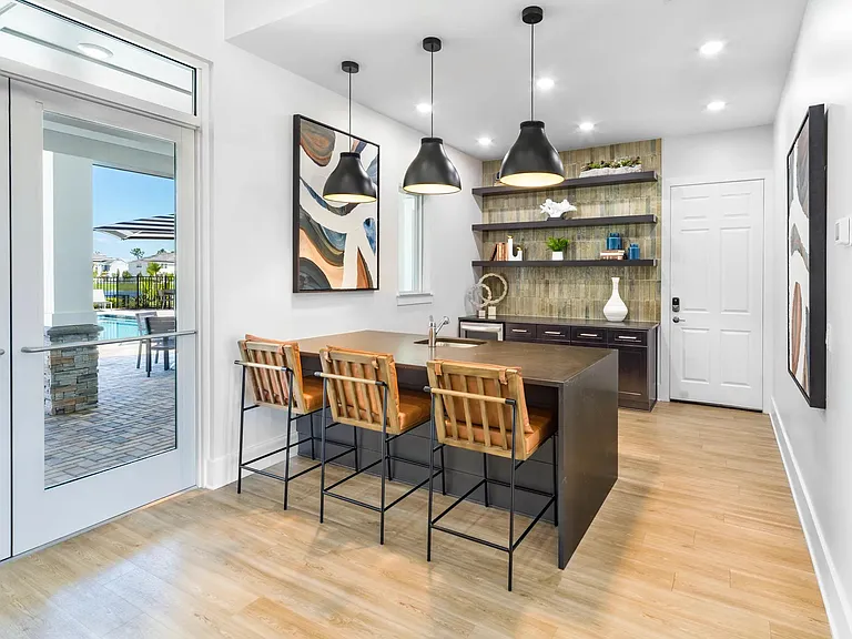A stylish clubroom at Amavi Kissimmee offers inviting seating and a warm, modern design with effortless access to the pool just outside.