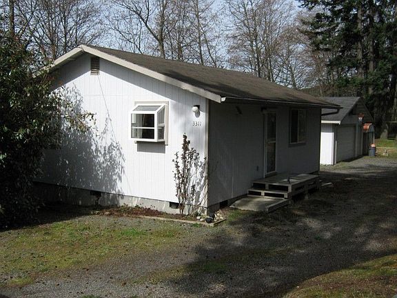 Front of the home with shadows from trees.