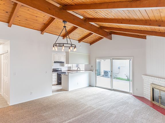 Living room with vaulted wood ceiling and wood-burning fireplace. New carpet installed in December 2025.