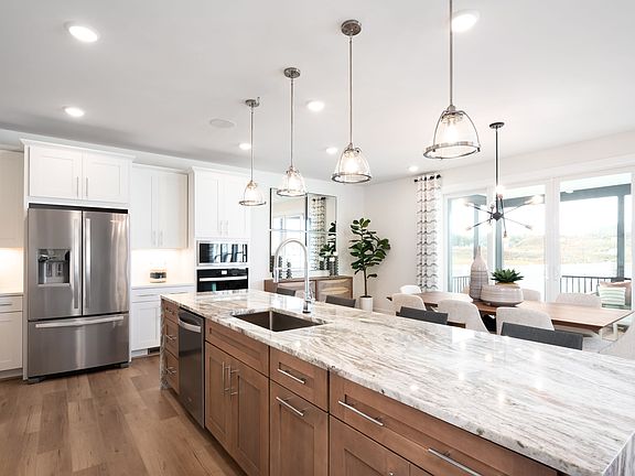 A modern, open-concept kitchen with white cabinets, wooden island countertop, and pendant lighting f
