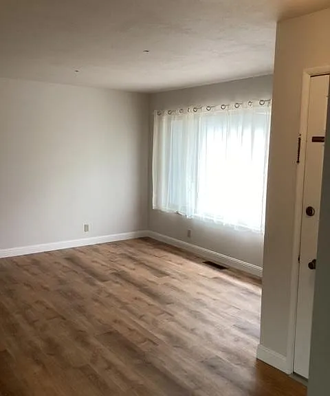 Living Room with Natural Light, Luxury Vinyl Plank flooring. Forced air heat vents.