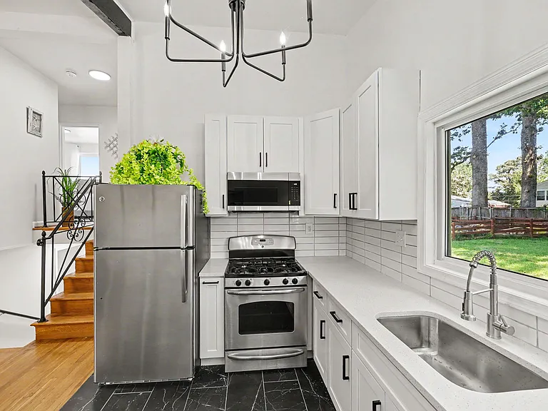 Updated kitchen with stainless appliances, ample cabinet storage, and a large sink set under a backyard-view window.