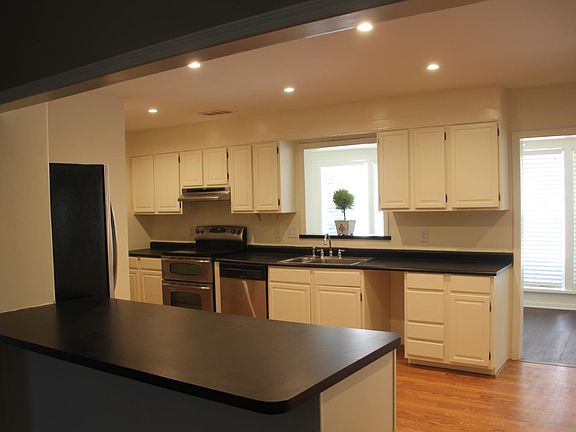 Large gourmet kitchen with hardwood floors, white cabinets,