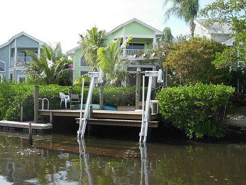 view of house, dock and boat lift from water