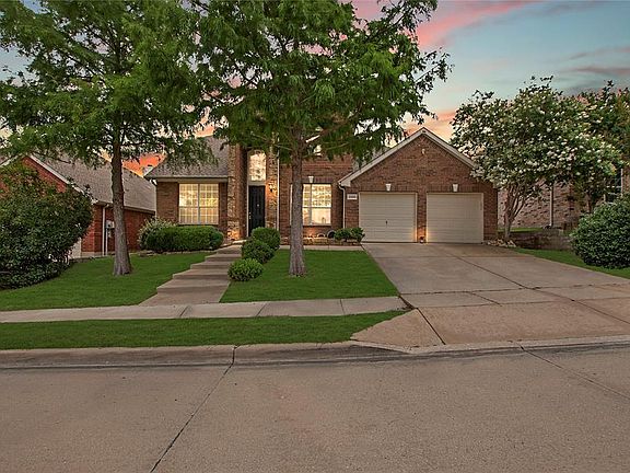 View of front of home featuring brick siding, a garage, driveway, and a yard