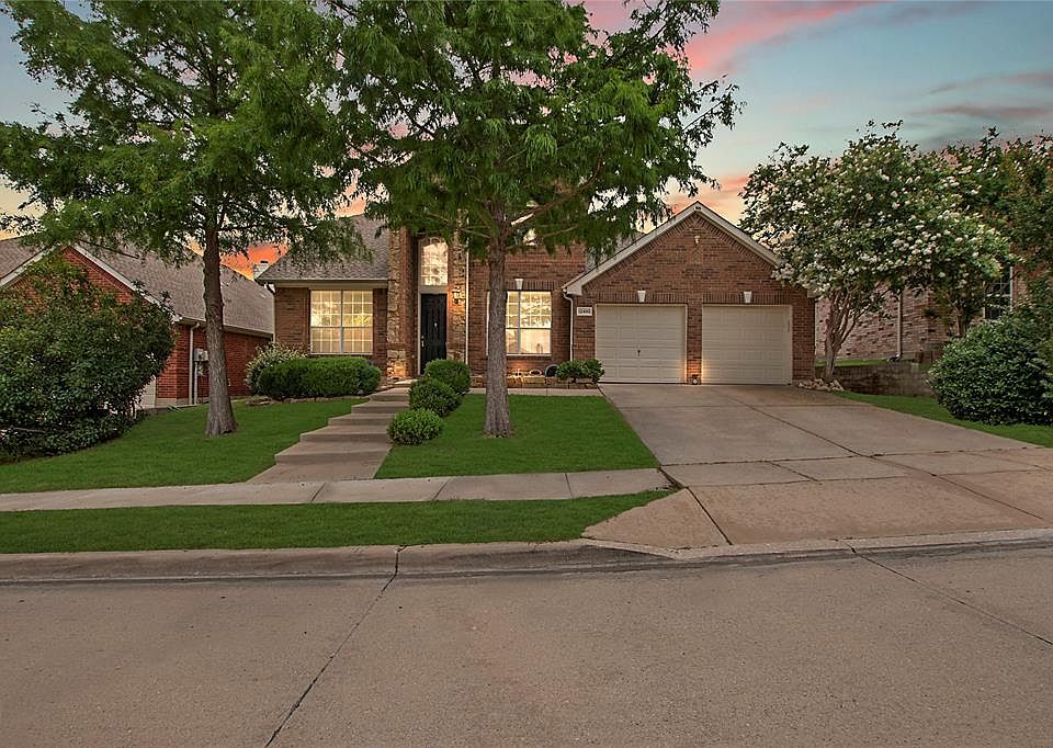 View of front of home featuring brick siding, a garage, driveway, and a yard