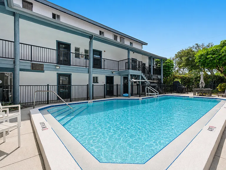 Sparkling blue swimming pool with lounge seating and a BBQ area.
