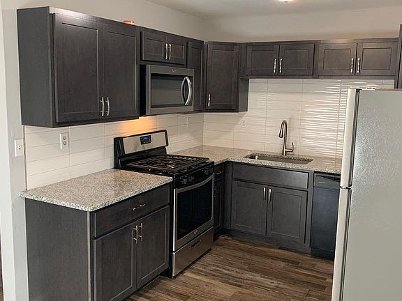 New kitchen cabinets, granite counters stainless range, microwave, dishwasher, & fridge, Dining room in background.