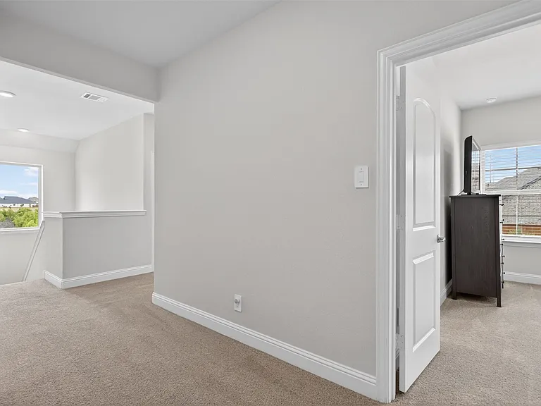 Carpeted upper-level landing featuring a wide doorway and a recessed window overlooking distant terrain