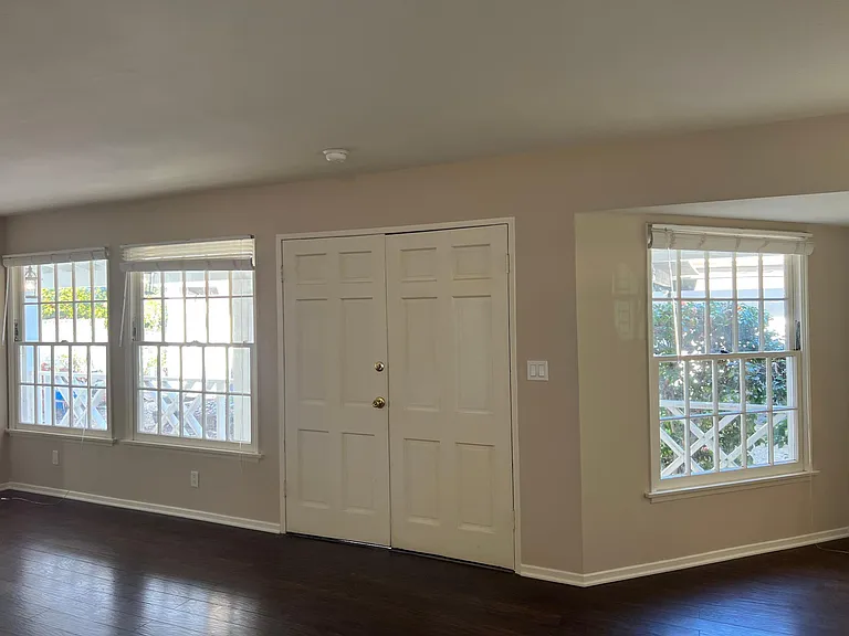 Living room with light filled windows overlooking the front porch and new landscaping. Notice the dark wood floors.