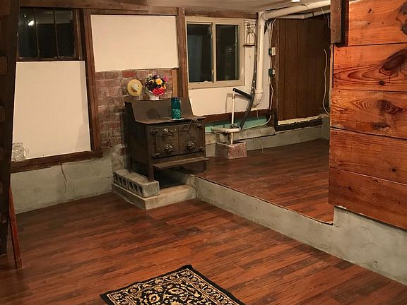 Large living Room with antique coal or wood stove and Original stained oak boards.