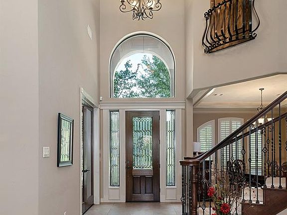 Dramatic foyer entryway with vaulted tray ceilings, elegant chandelier, & over-sized tile.