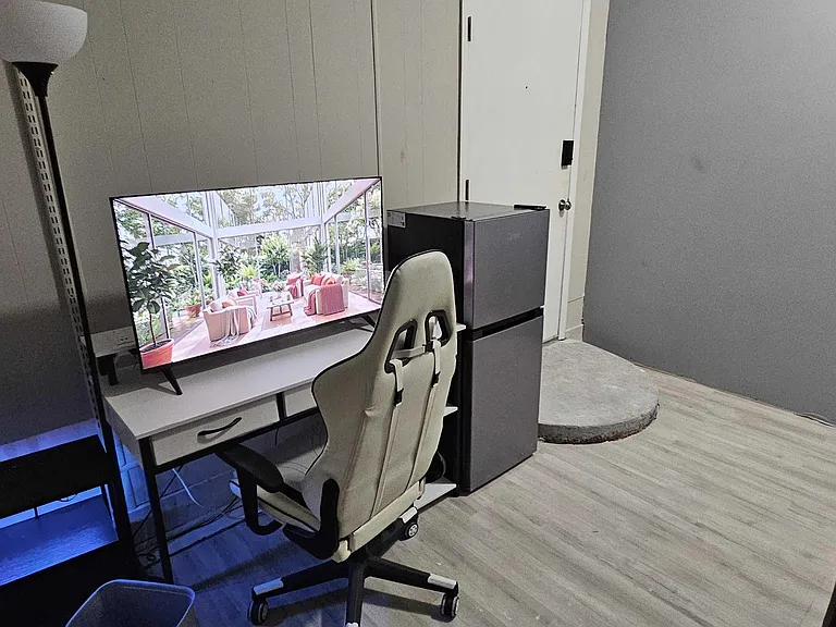 Private bedroom with durable flooring, neutral walls, and space for a desk setup plus a mini fridge for convenience.