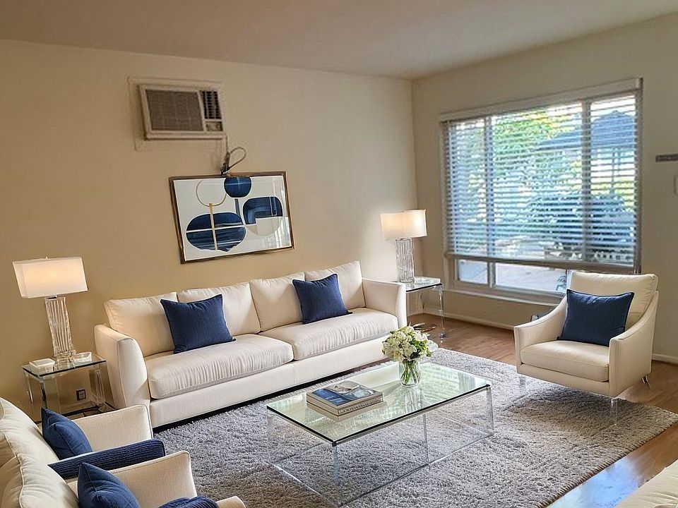 Living room with large picture window with horizontal custom blinds; next to separate dining room adjacent to kitchen (comes unfurnished)