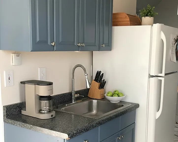 Character-rich vintage kitchen with retro vibe showcasing the cute blue cupboards, classic linoleum flooring, complete with dishwasher.
