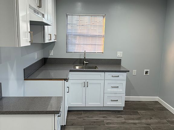 The kitchen cabinets include stainless handles to give it a contemporary look with recess lights and a grey ceramic plank type tile