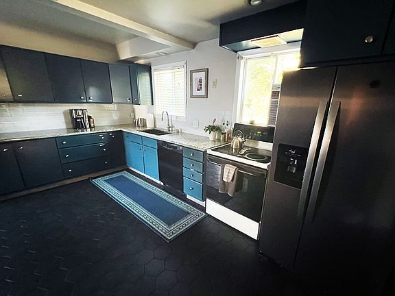 Large kitchen updated in 2023 with double door refridgerator, electric oven, and plenty of cabinet space and room for dining room table. Disposal new with extender sink head and dish washer machine. Window unit AC in photo has been removed.