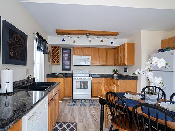 Fully equipped kitchen with stove, microwave, refrigerator, pots, pans and dishes.