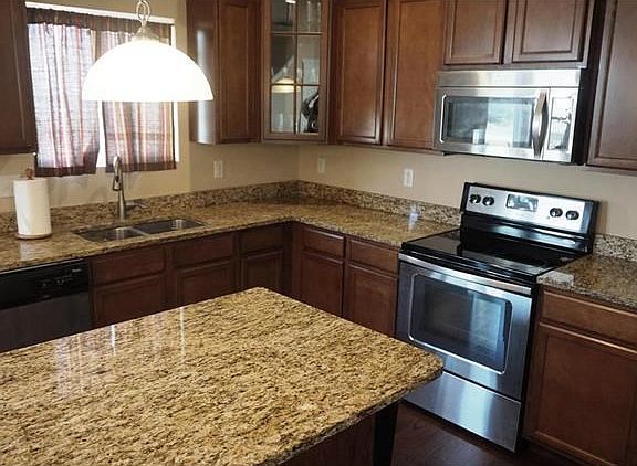 Granite countertops on center island with bar overhang. Stainless steel upgraded appliances. Upgraded glass fronted corner cabinet; upgraded pull-down goose neck faucet.