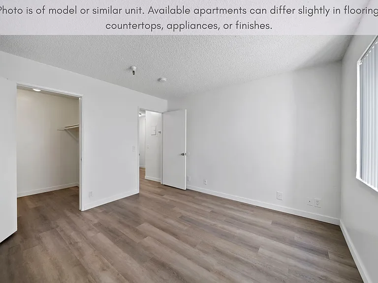 Comfortable bedroom with modern flooring, a walk-in closet, and plenty of natural light.